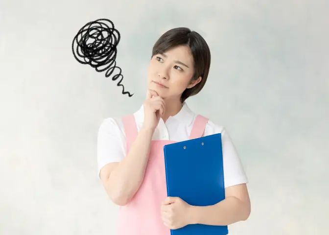 介護職員の格好をして悩んでいる様子の女性