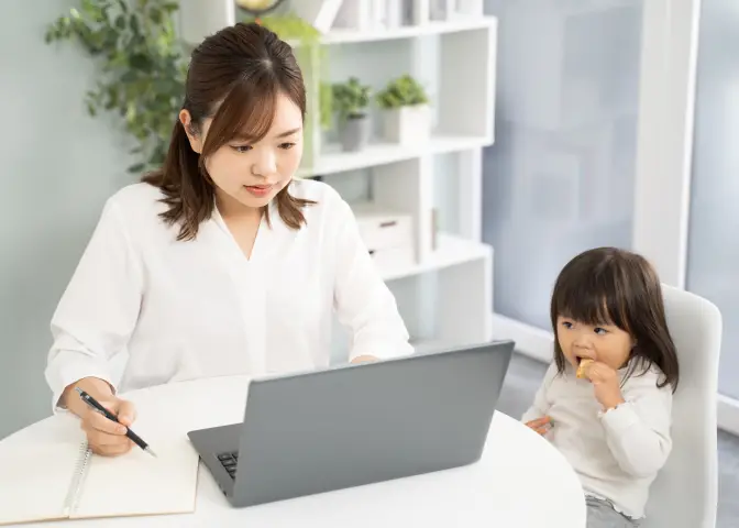 小さな子どもを隣に座らせてパソコン学習している女性の写真